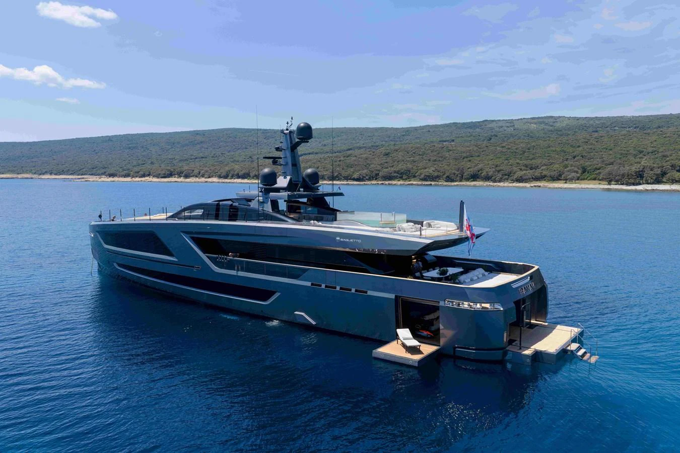 A sleek and modern yacht is anchored in calm blue waters with a scenic coastline in the background. aboard PANAM Yacht for Sale