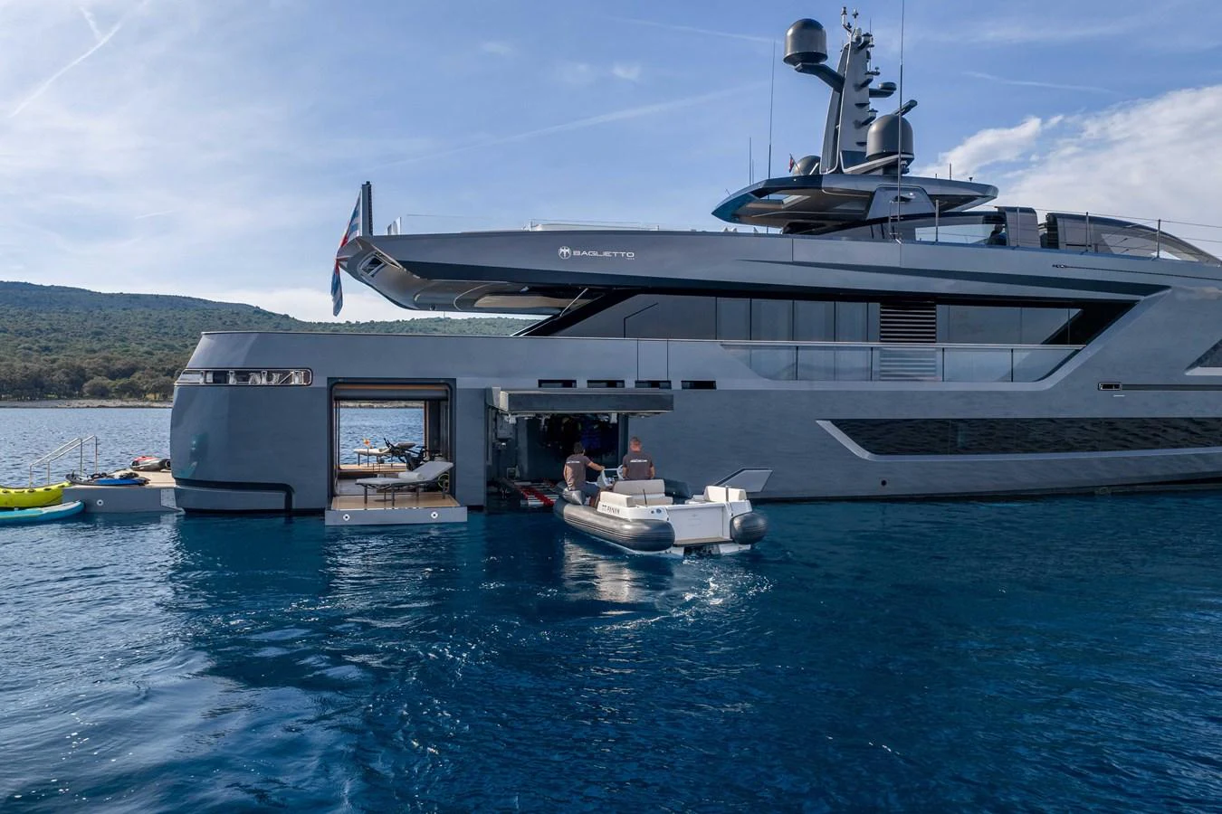 A sleek, modern yacht with a tender being deployed from the side garage, set against a serene coastal backdrop. aboard PANAM Yacht for Sale