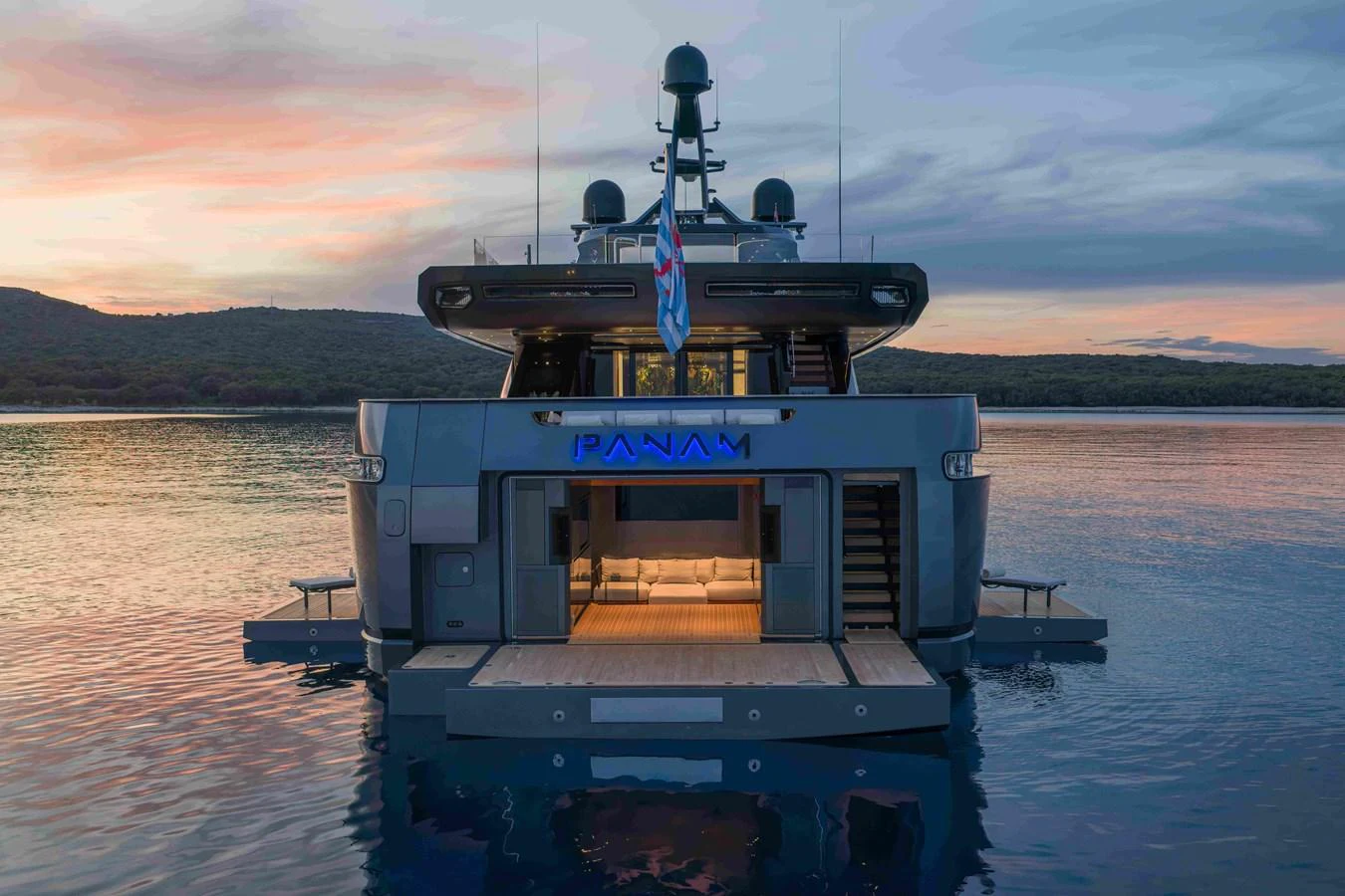 The yacht's aft deck is beautifully illuminated against a serene sunset backdrop. aboard PANAM Yacht for Sale