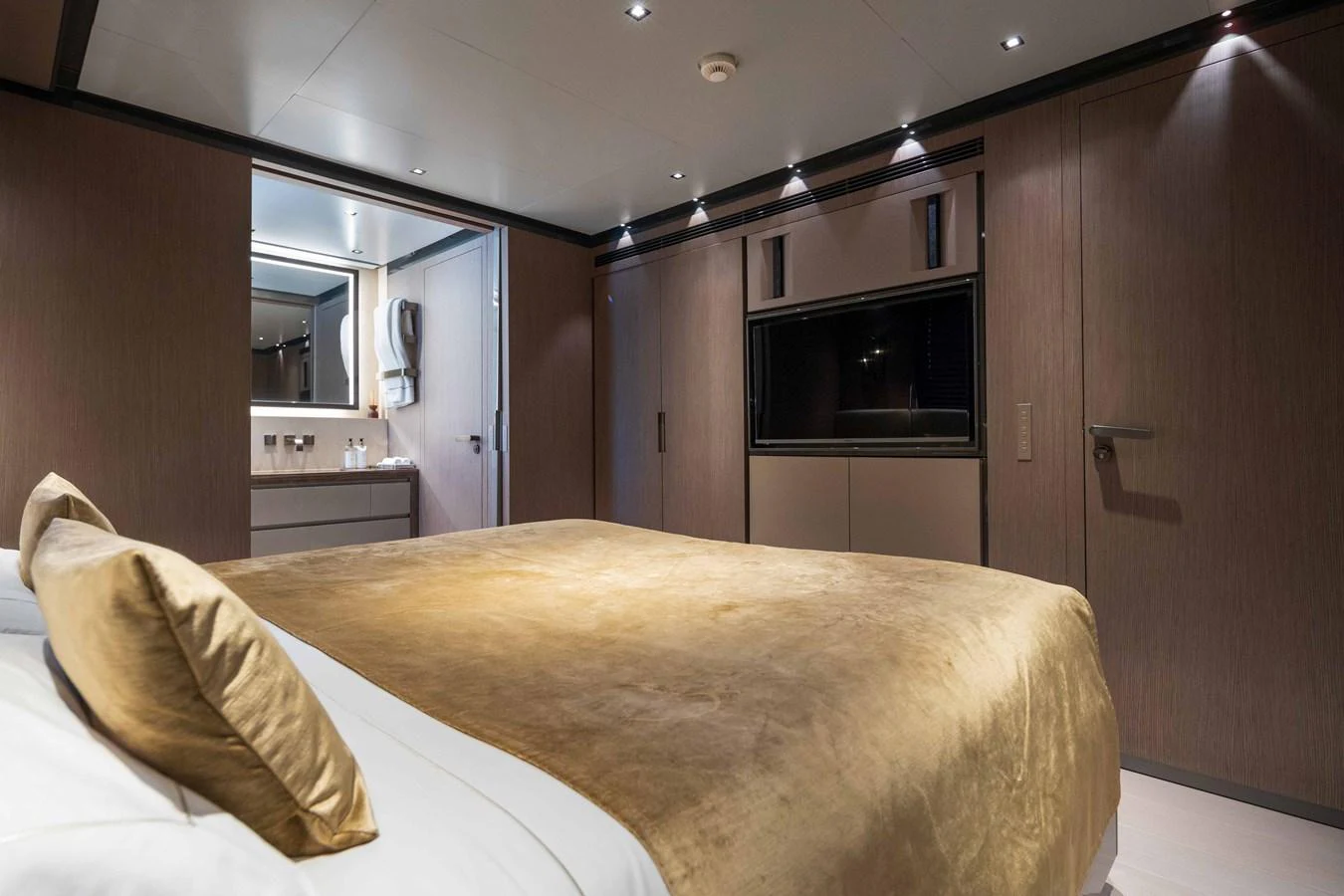 The stateroom features a luxurious bed with a golden bedspread and modern amenities. aboard PANAM Yacht for Sale