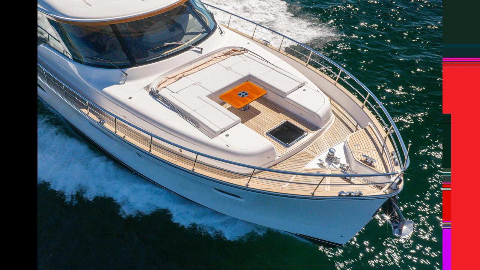 The yacht's sleek foredeck features a spacious sunbathing area with plush cushions and a stylish wooden table. aboard LYRICA Yacht for Sale