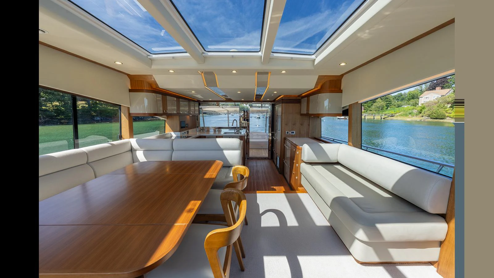 The spacious salon features large windows, a skylight, and elegant seating with a dining area. aboard LYRICA Yacht for Sale