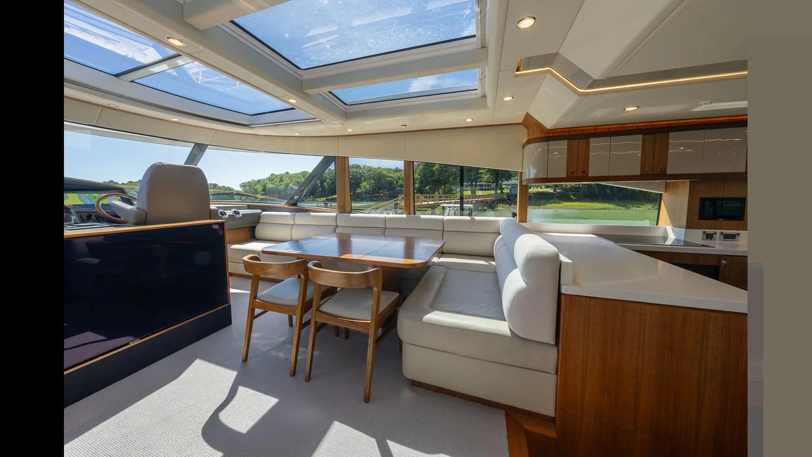 The salon features large windows and skylights, offering a bright and airy atmosphere with comfortable seating and a dining area. aboard LYRICA Yacht for Sale