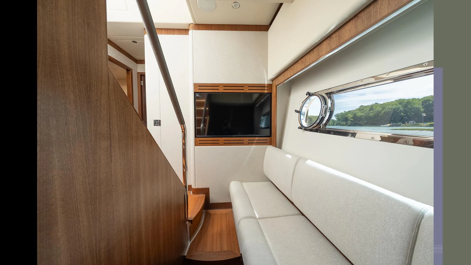 The yacht's interior features a cozy seating area with a large window offering scenic views. aboard LYRICA Yacht for Sale