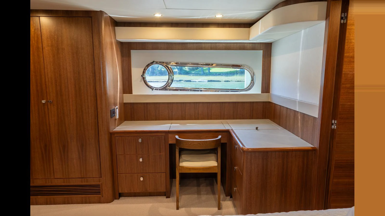 A cozy cabin with a wooden desk and chair, complemented by a large window offering a serene view. aboard LYRICA Yacht for Sale