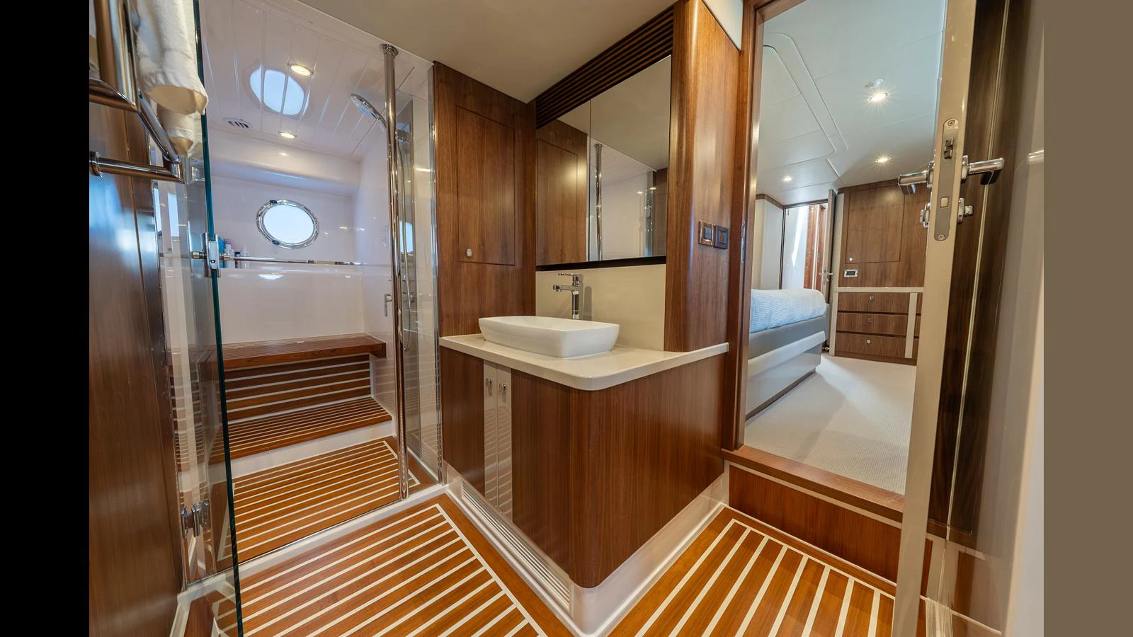 The yacht's bathroom features elegant wood paneling and a modern sink with a spacious shower area. aboard LYRICA Yacht for Sale