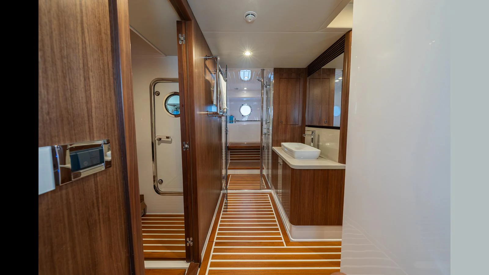The image showcases a sleek and modern yacht interior with wooden finishes and a well-lit corridor. aboard LYRICA Yacht for Sale