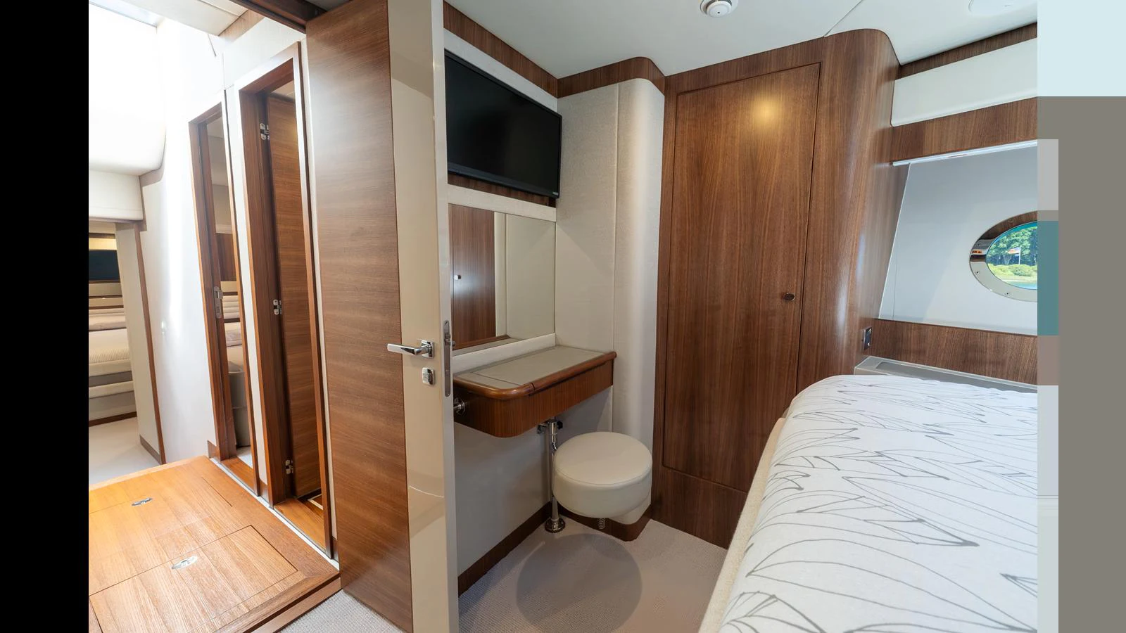 The stateroom features elegant wood paneling, a comfortable bed, and a small vanity area. aboard LYRICA Yacht for Sale