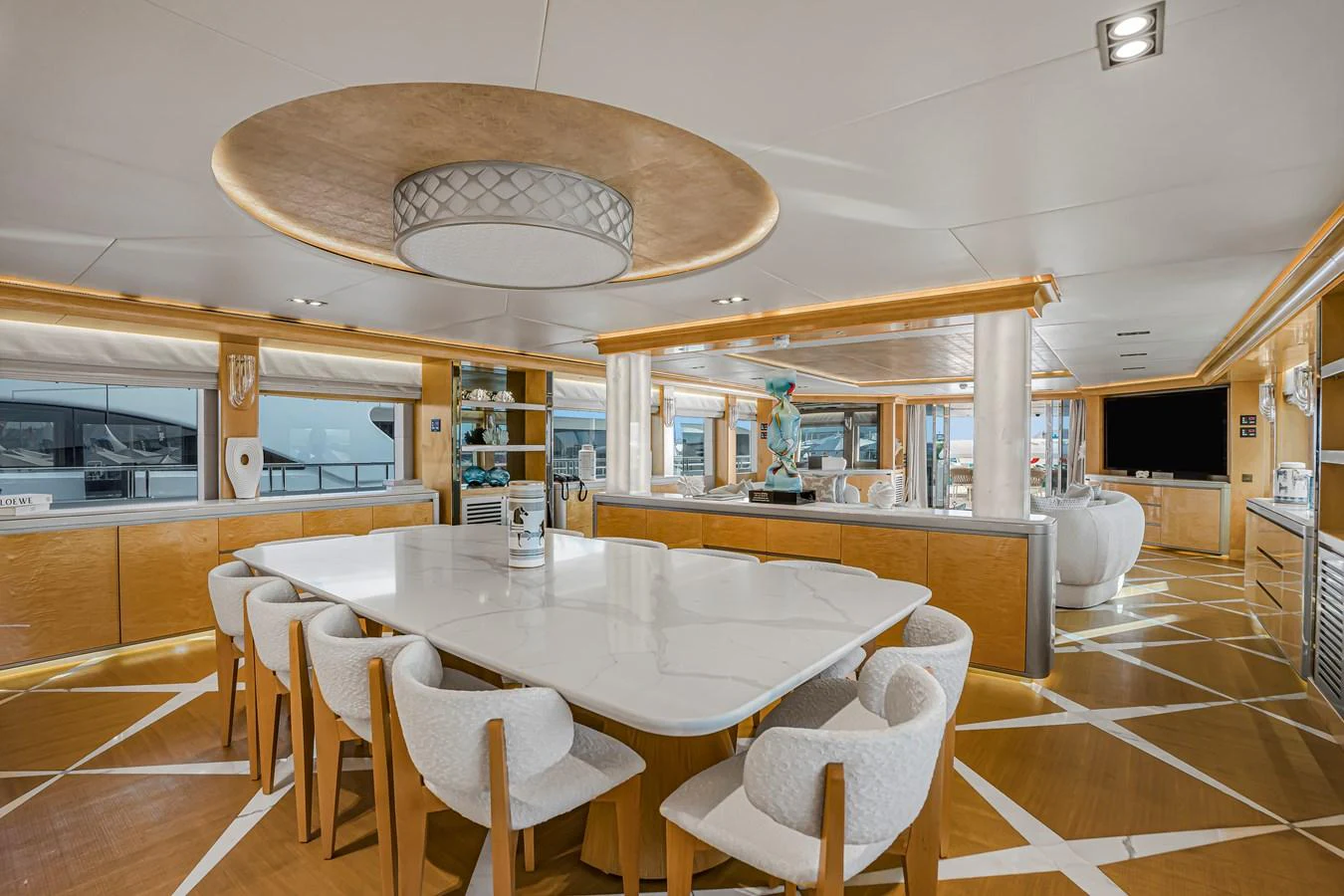 The yacht's dining area features a large, elegant table surrounded by plush chairs, with ample natural light and luxurious decor. aboard ATLANTIS Yacht for Sale