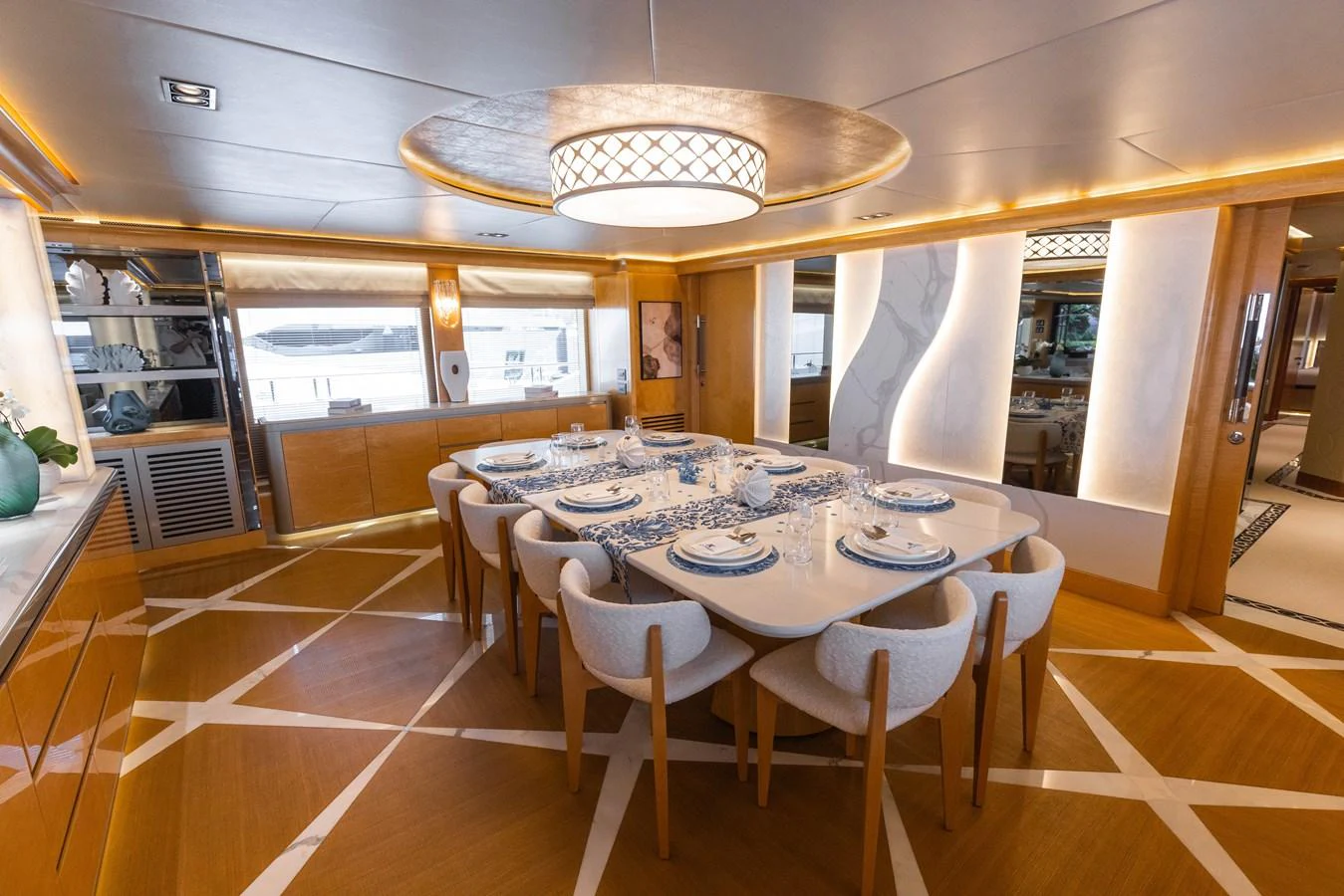 The yacht's dining area features a large table set for a formal meal, surrounded by elegant chairs and illuminated by a stylish ceiling light. aboard ATLANTIS Yacht for Sale