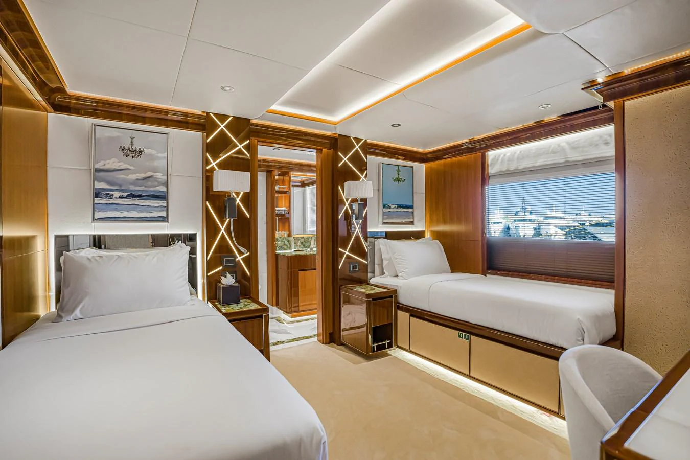 The guest stateroom features twin beds, elegant wood paneling, and modern lighting. aboard ATLANTIS Yacht for Sale