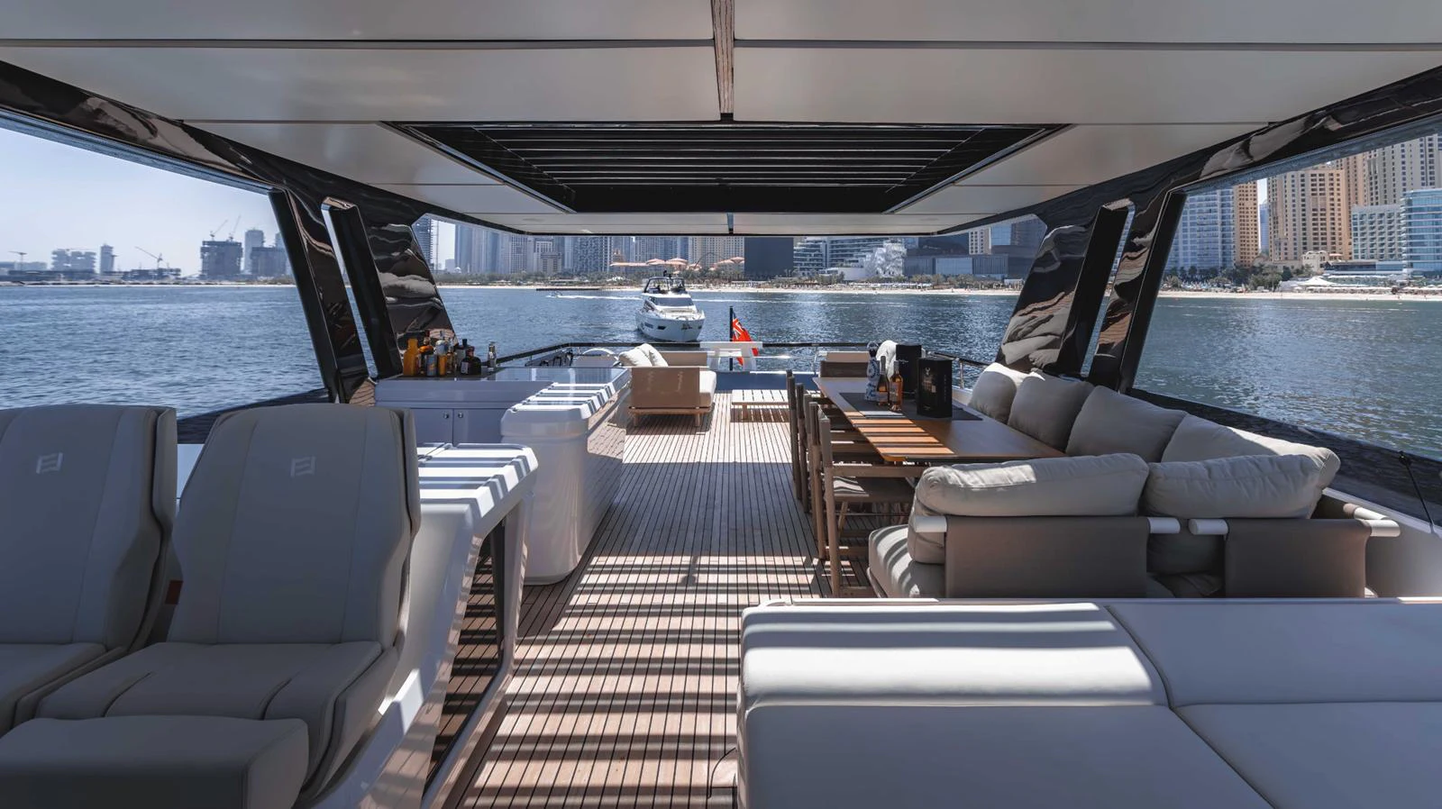 The aft deck features luxurious seating and dining areas with a stunning waterfront view. aboard AMANI Yacht for Sale