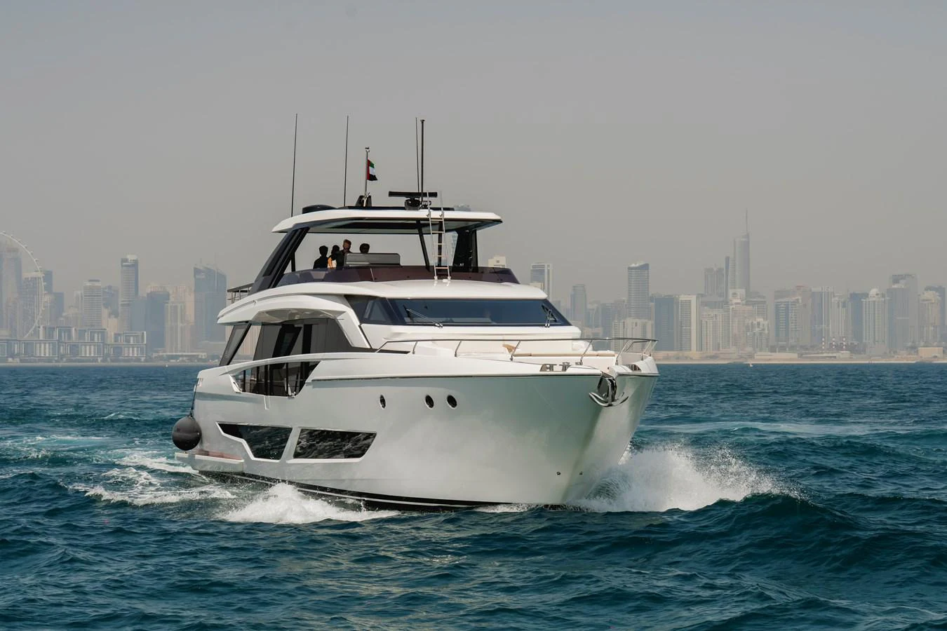 A sleek yacht cruises through the water with a city skyline in the background. aboard AMANI Yacht for Sale