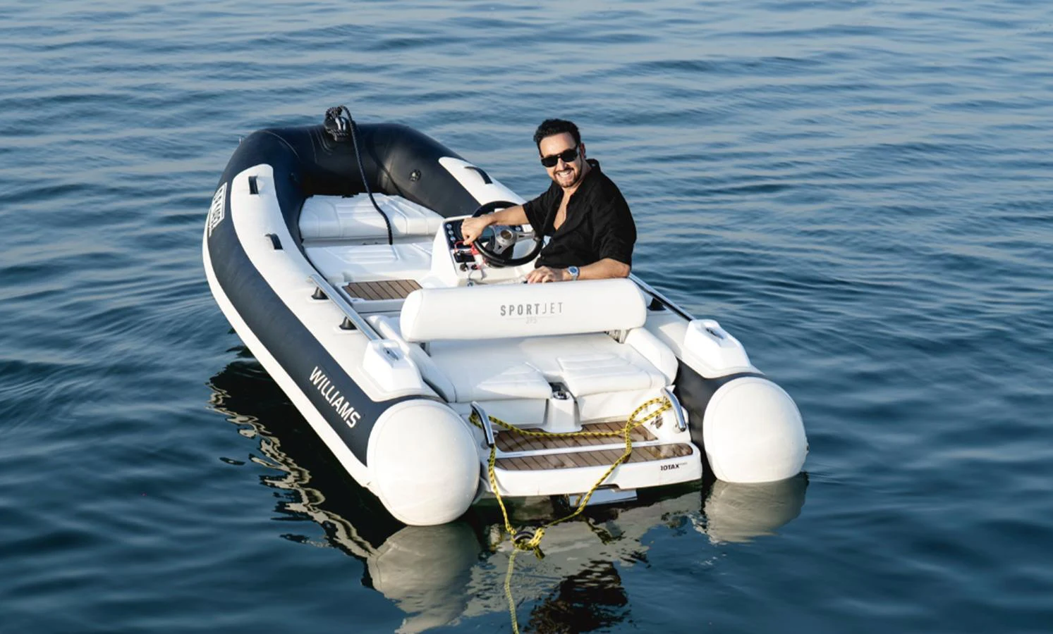 A sleek tender with a person at the helm, floating on calm waters. aboard AMANI Yacht for Sale