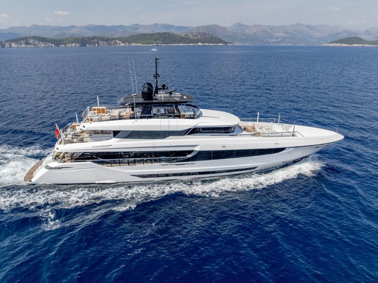 A sleek and modern yacht cruising on calm blue waters with a scenic coastline in the background. aboard TOY Yacht for Sale