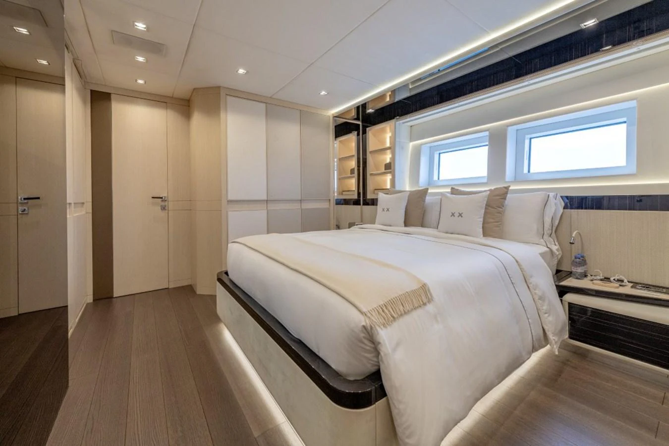 The stateroom features a plush bed with elegant linens and ample storage space, illuminated by natural light from the windows. aboard TOY Yacht for Sale