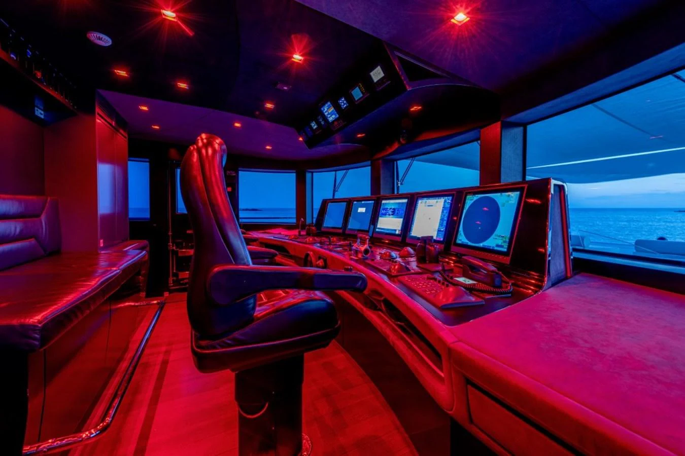 The helm station features advanced navigation equipment and luxurious seating, bathed in ambient lighting. aboard TOY Yacht for Sale