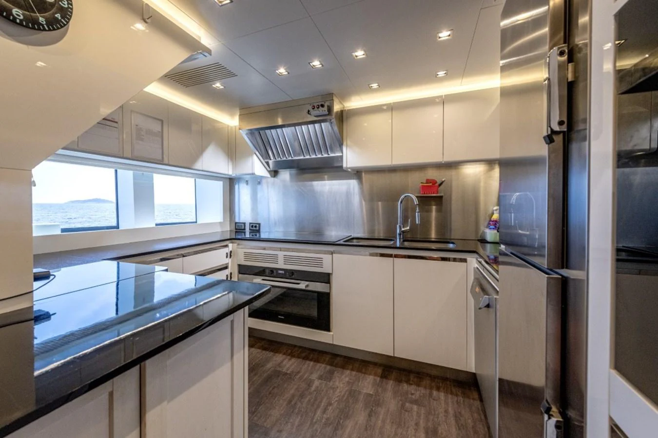 The modern galley features sleek cabinetry, stainless steel appliances, and ample counter space with ocean views. aboard TOY Yacht for Sale