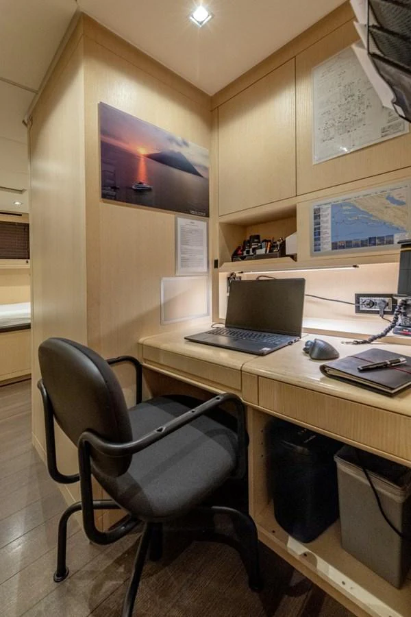 A cozy onboard office space with a desk, chair, and various navigational charts and equipment. aboard TOY Yacht for Sale
