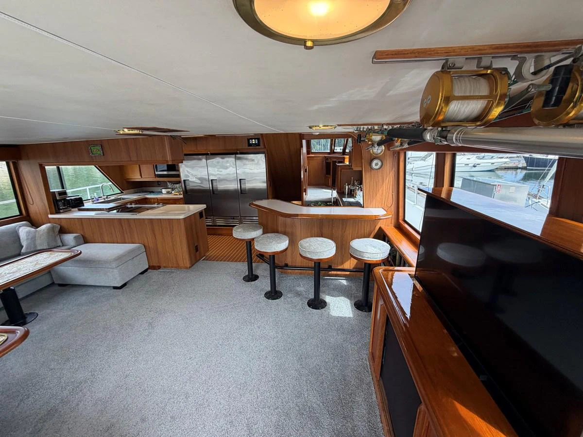 The yacht's salon features a cozy seating area, a bar with stools, and large windows offering ample natural light. aboard OCEAN PACIFIC Yacht for Sale