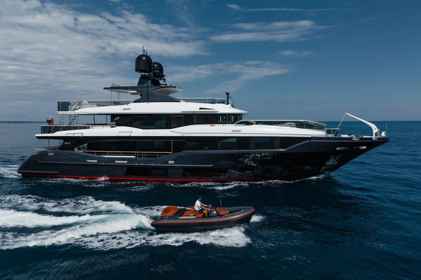A sleek yacht cruises on the open sea accompanied by a tender boat. aboard ADVA Yacht for Sale
