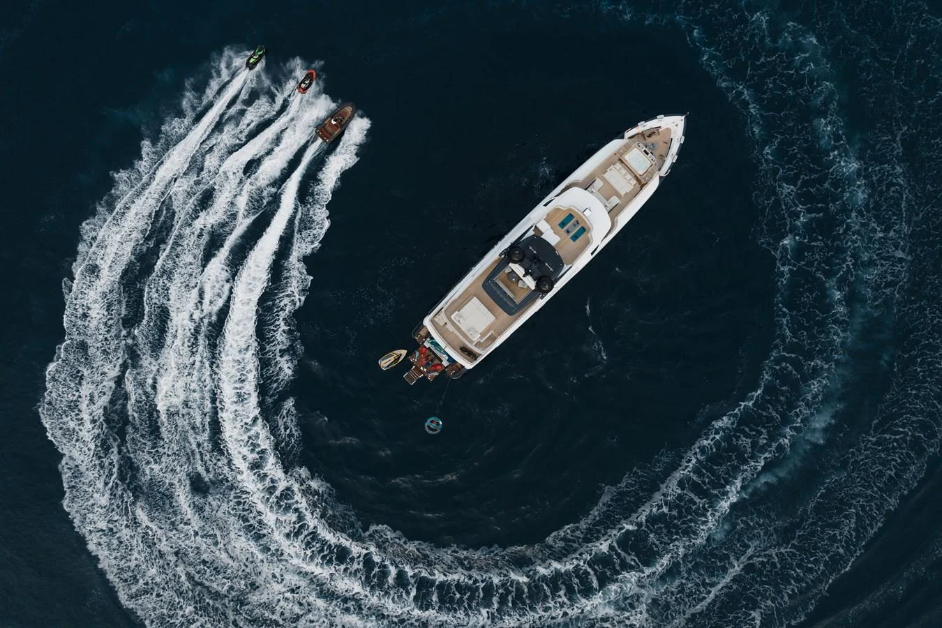 Aerial view of a yacht surrounded by watercraft creating dynamic patterns in the water. aboard ADVA Yacht for Sale