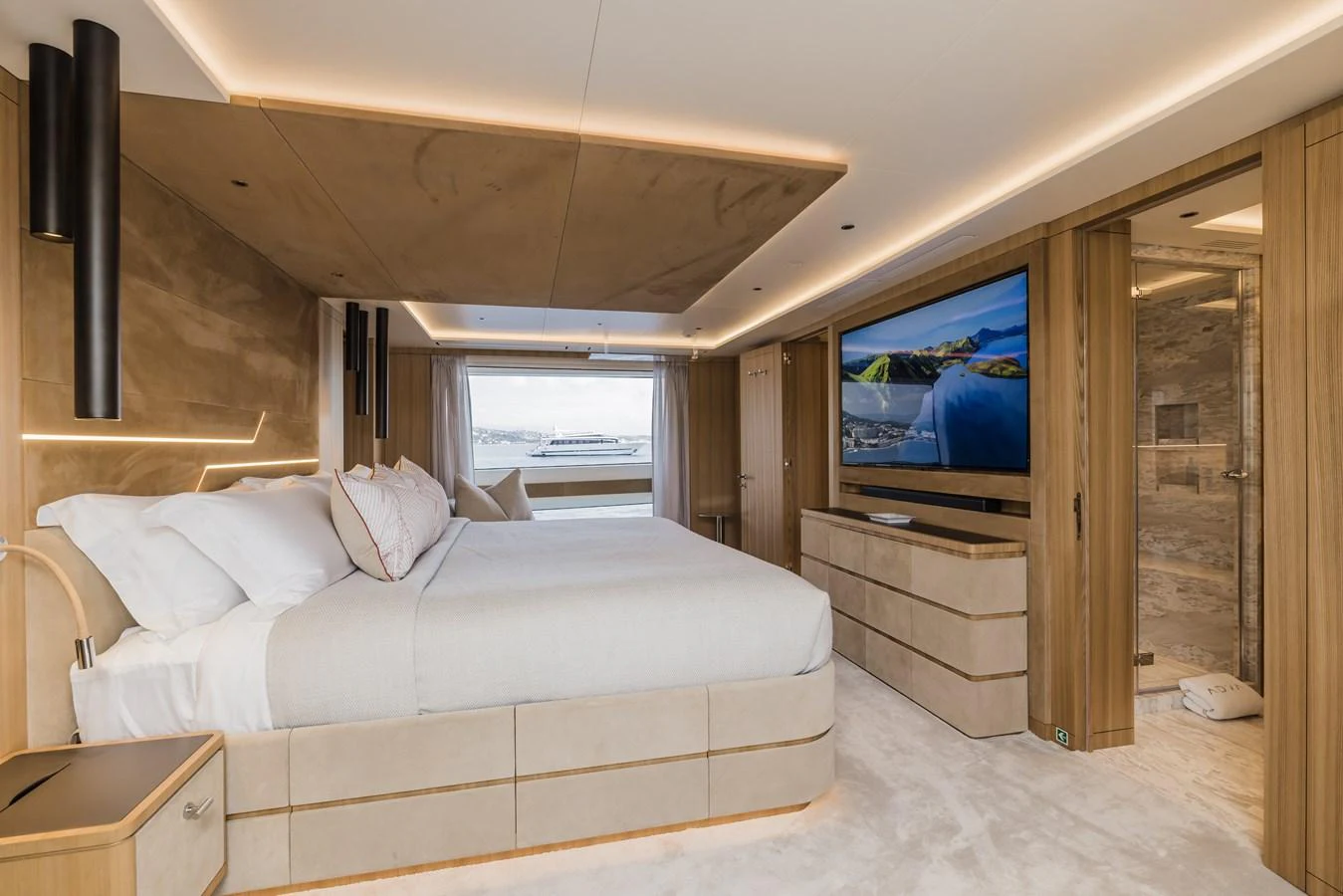 The master stateroom features a luxurious bed, modern decor, and a large flat-screen TV. aboard ADVA Yacht for Sale