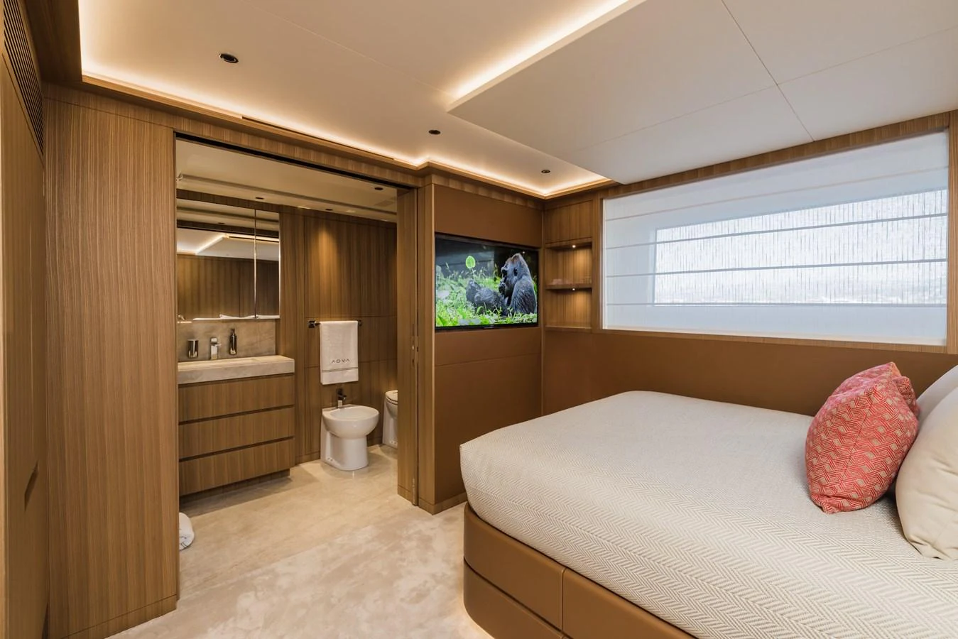 The stateroom features a comfortable bed, modern wood paneling, and an ensuite bathroom. aboard ADVA Yacht for Sale