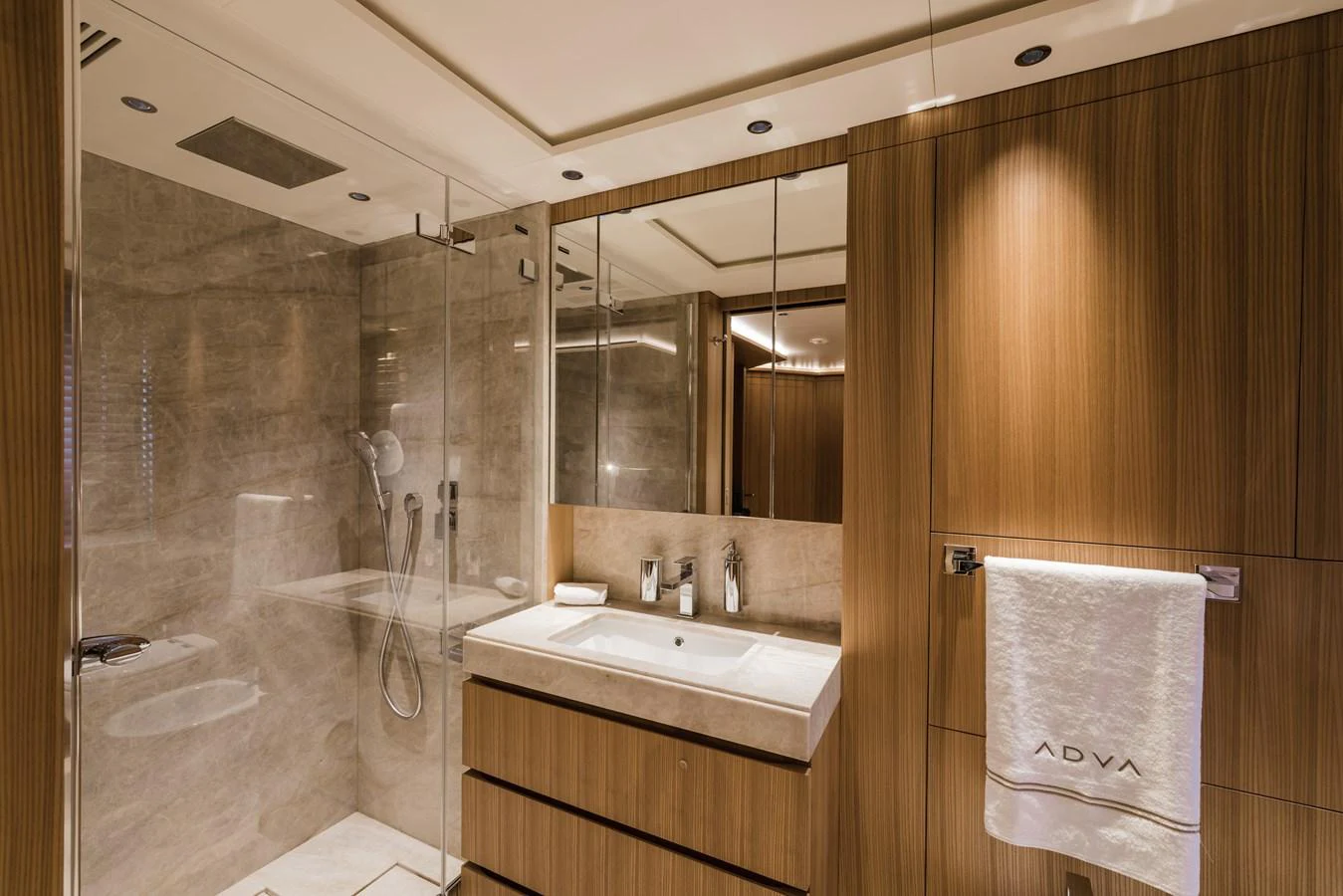 The yacht's bathroom features luxurious wood paneling and a spacious glass-enclosed shower. aboard ADVA Yacht for Sale
