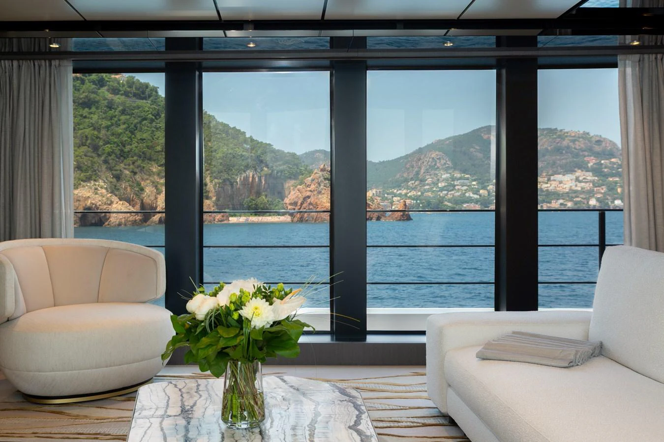 The salon offers a serene view of the sea through large windows, complemented by elegant furnishings. aboard LADY DIA Yacht for Sale