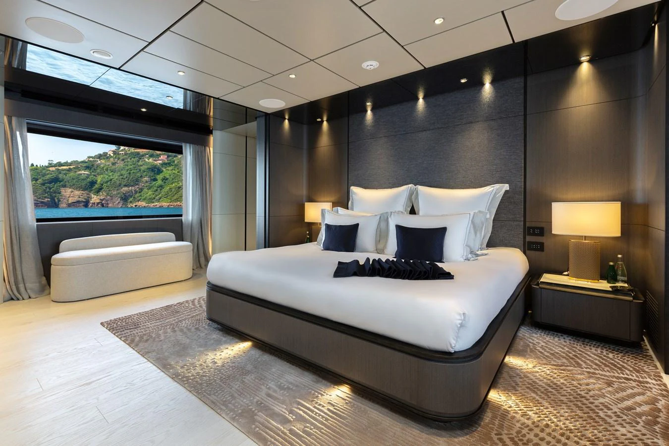 The master stateroom features a luxurious bed with elegant bedding and a scenic view through large windows. aboard LADY DIA Yacht for Sale