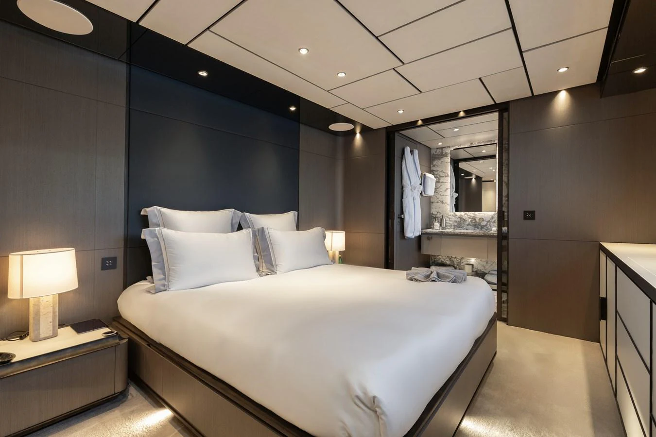 The master stateroom features a luxurious bed with elegant lighting and a modern ensuite bathroom. aboard LADY DIA Yacht for Sale