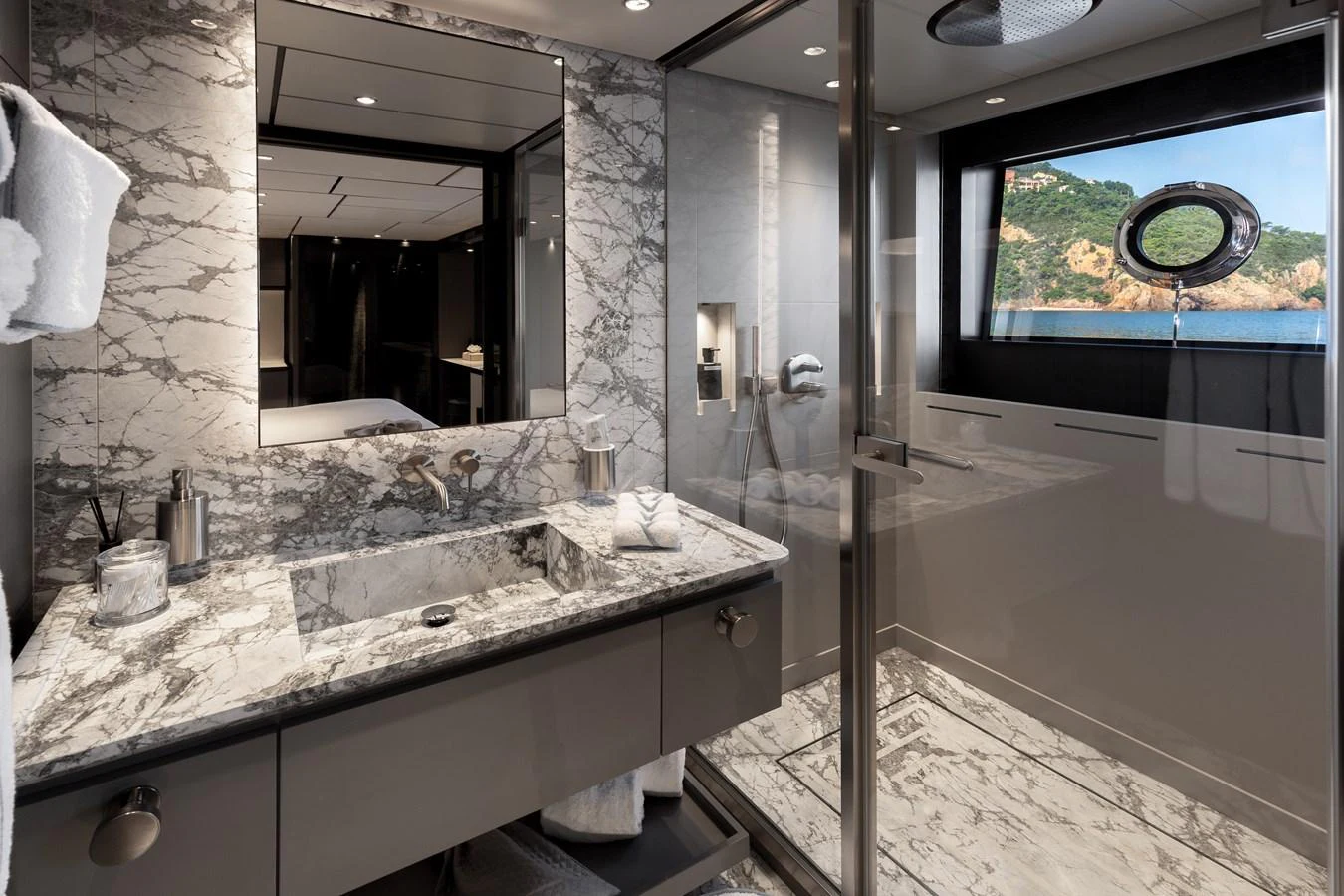 This luxurious yacht bathroom features elegant marble surfaces and a spacious shower area with a scenic view. aboard LADY DIA Yacht for Sale
