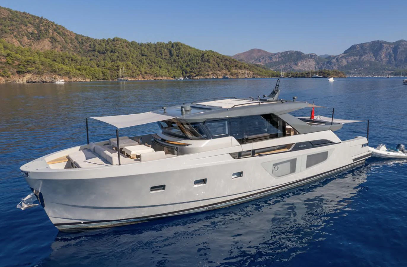 This sleek yacht cruises gracefully on calm blue waters with a scenic coastal backdrop. aboard OUT OF THE BLUE Yacht for Sale