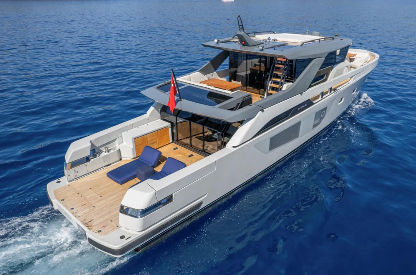 A sleek yacht cruises through clear blue waters, showcasing its modern design and spacious deck. aboard OUT OF THE BLUE Yacht for Sale
