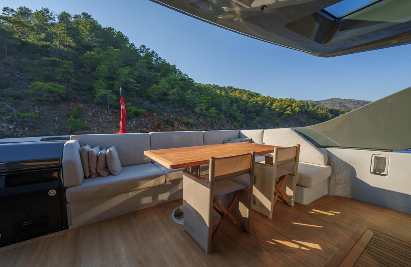 The aft deck features a comfortable seating area with a wooden dining table, perfect for enjoying meals with a scenic view. aboard OUT OF THE BLUE Yacht for Sale