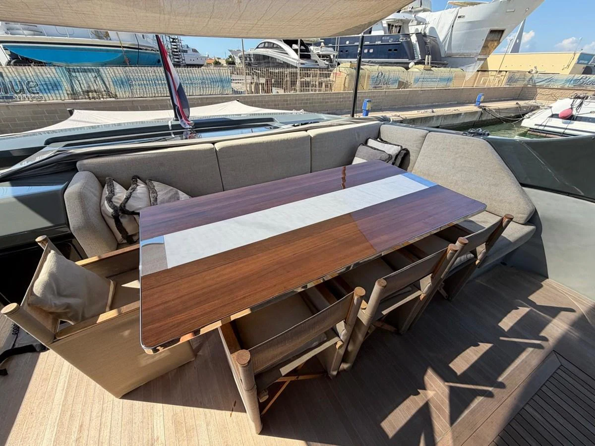 The aft deck features a stylish dining area with a polished wooden table and comfortable seating. aboard OUT OF THE BLUE Yacht for Sale