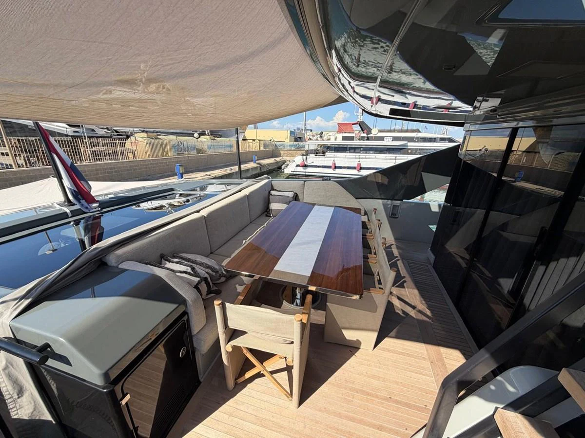 The aft deck features a comfortable dining area with a wooden table and cushioned seating, shaded by a canopy. aboard OUT OF THE BLUE Yacht for Sale