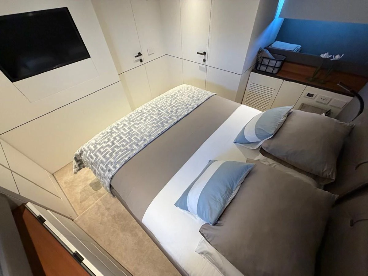 A cozy stateroom featuring a comfortable bed with modern decor and a wall-mounted TV. aboard OUT OF THE BLUE Yacht for Sale