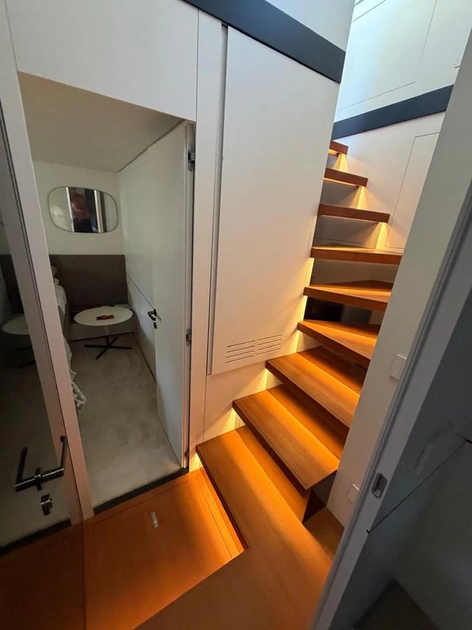 A modern yacht interior featuring a sleek wooden staircase leading to an upper level. aboard OUT OF THE BLUE Yacht for Sale