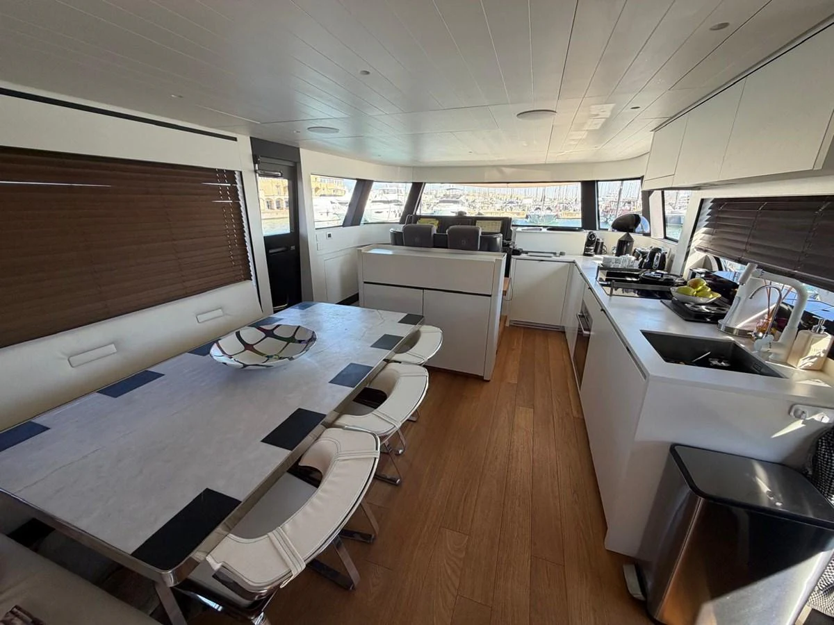 The yacht's galley features a modern dining area and a well-equipped kitchen with ample natural light. aboard OUT OF THE BLUE Yacht for Sale