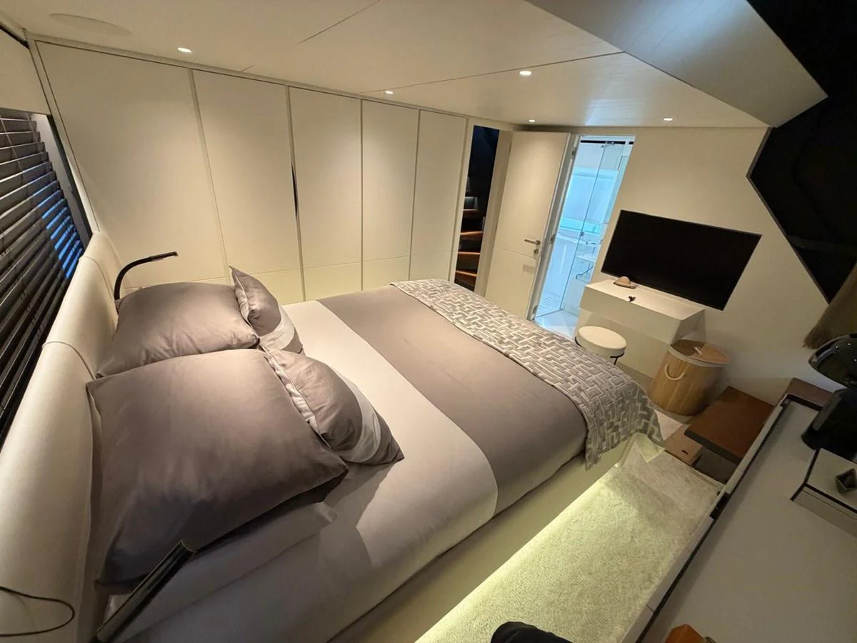 The stateroom features a plush bed with modern decor and a flat-screen TV. aboard OUT OF THE BLUE Yacht for Sale