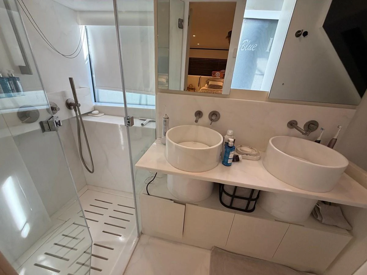 A modern yacht bathroom featuring dual sinks and a spacious shower area. aboard OUT OF THE BLUE Yacht for Sale