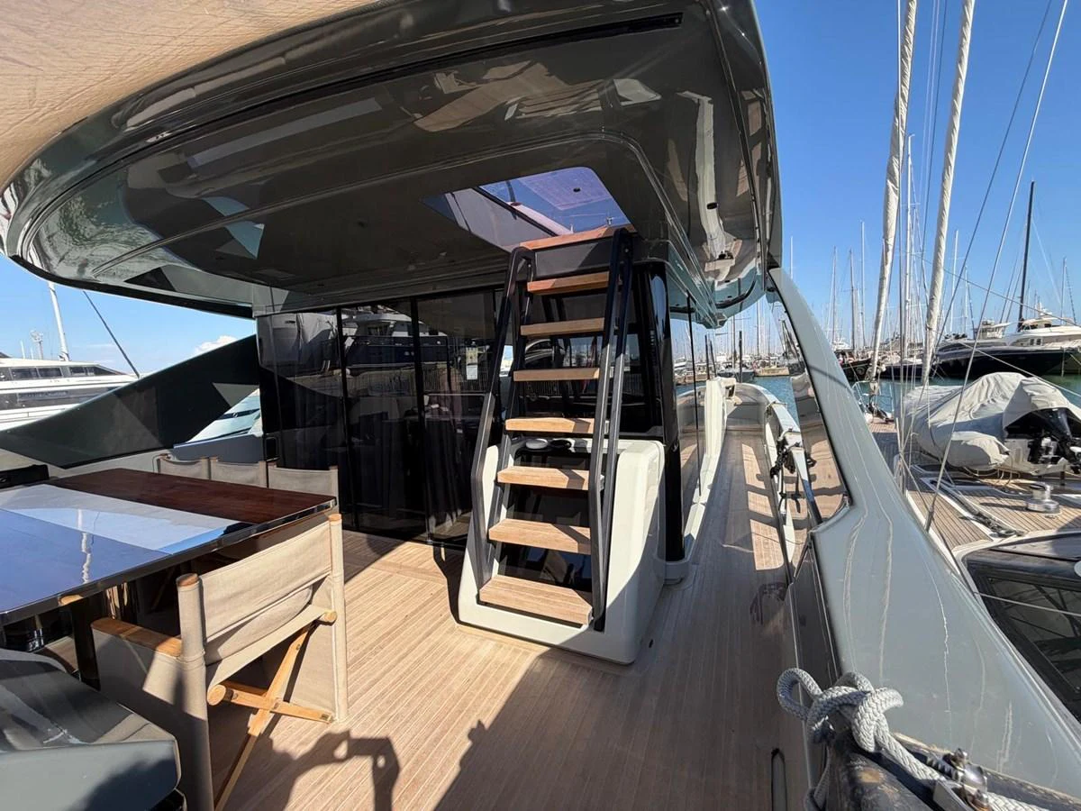 The aft deck features a stylish seating area with a staircase leading to the upper deck, showcasing modern design elements. aboard OUT OF THE BLUE Yacht for Sale