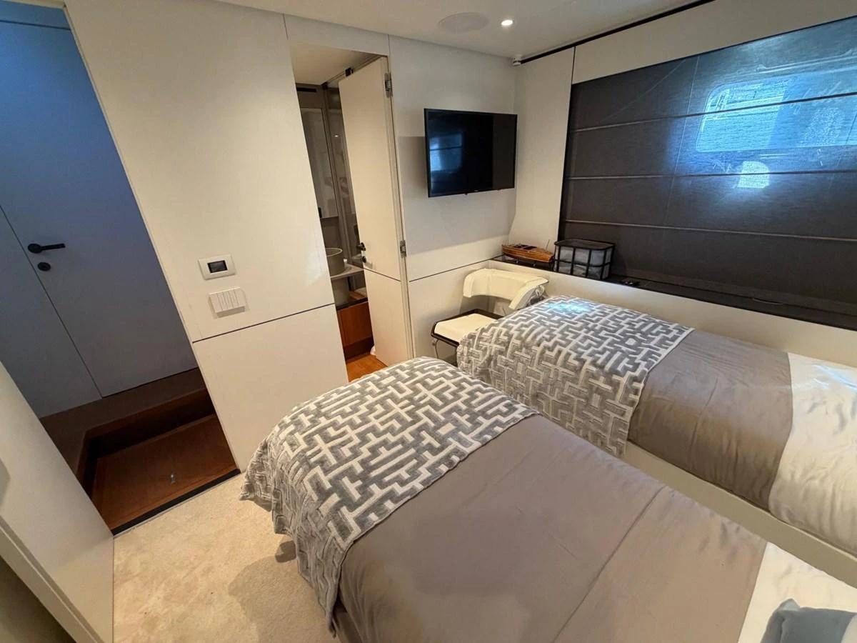The guest stateroom features twin beds with modern bedding and a sleek, minimalist design. aboard OUT OF THE BLUE Yacht for Sale