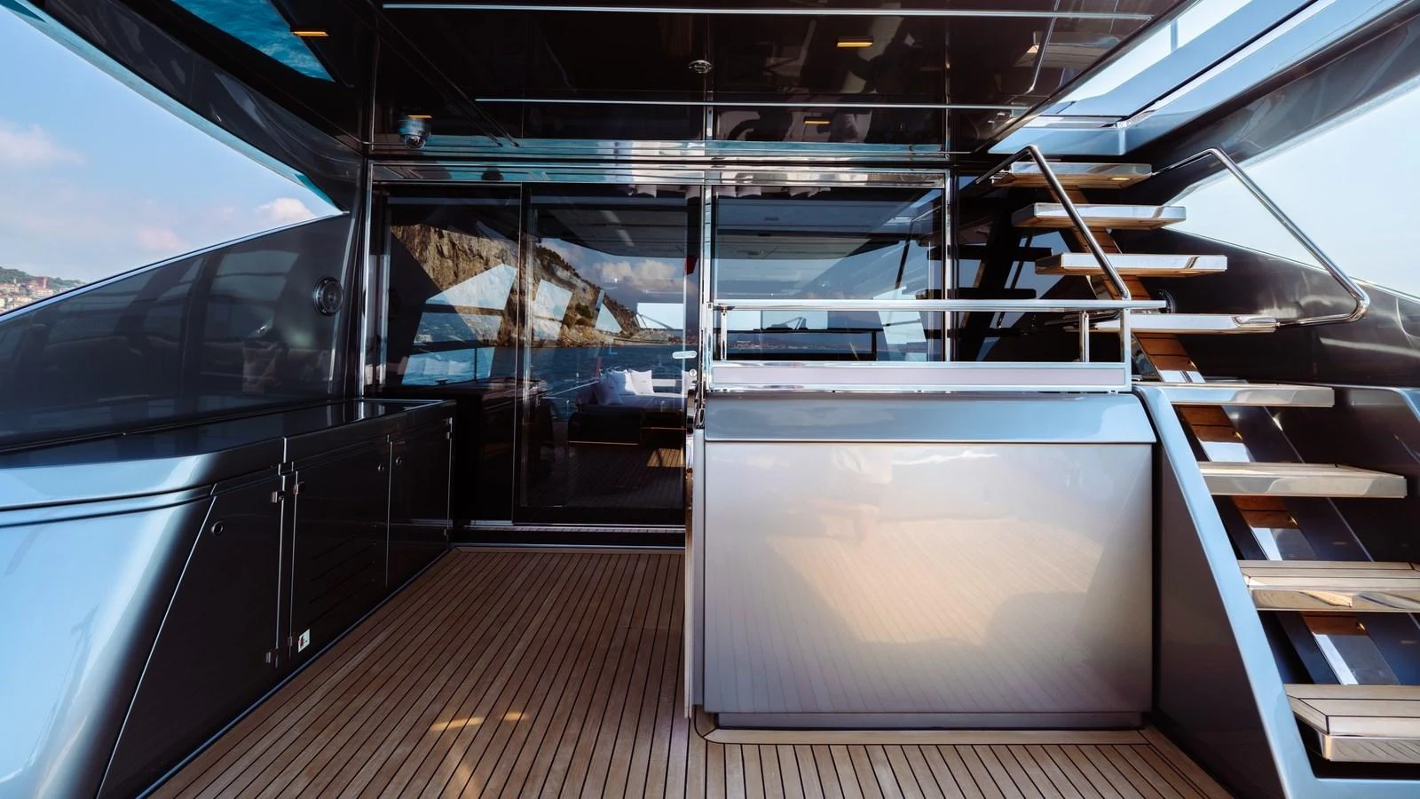 The aft deck features sleek design elements with polished surfaces and a staircase leading to the upper deck. aboard MAYAR Yacht for Sale