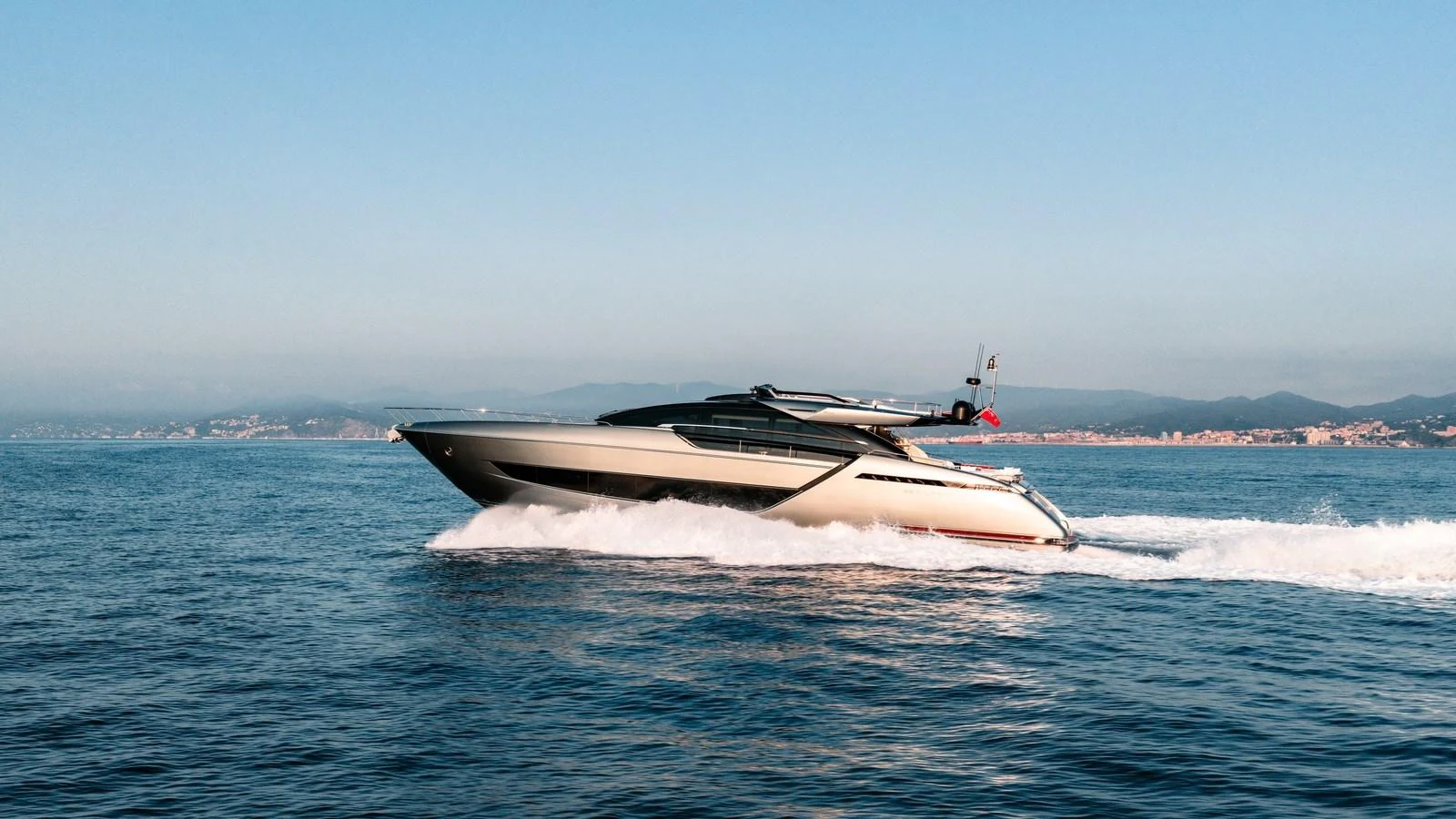 A sleek yacht cruises swiftly across calm waters with a scenic coastline in the background. aboard MAYAR Yacht for Sale