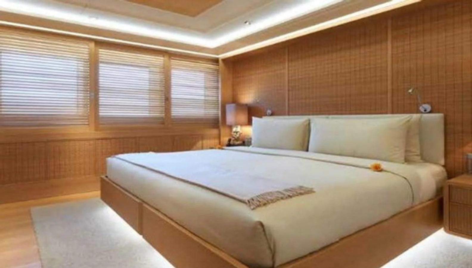 The stateroom features a spacious bed with elegant wooden paneling and soft lighting. aboard DYTAN Yacht for Sale
