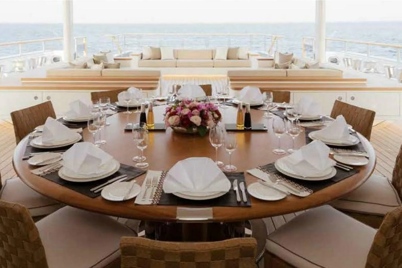 The yacht features an elegant dining area with a round table set for a meal, offering a view of the sea. aboard DYTAN Yacht for Sale