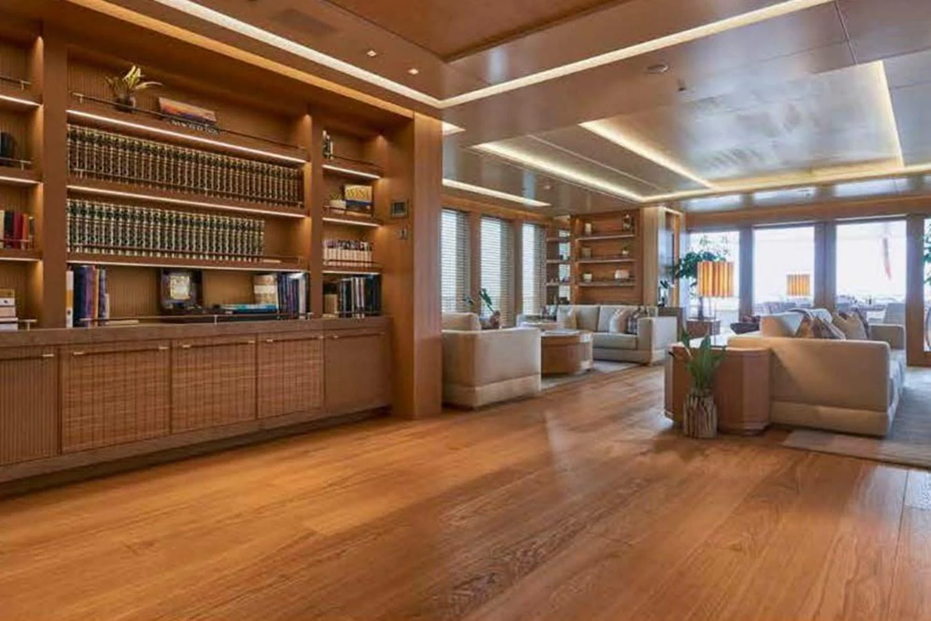 The spacious salon features elegant wooden flooring, comfortable seating, and a well-stocked bookshelf, creating a warm and inviting atmosphere. aboard DYTAN Yacht for Sale